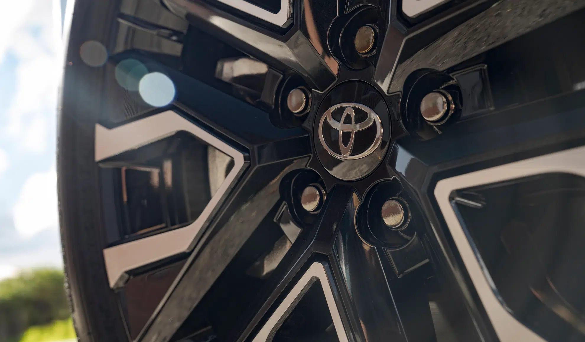 Close-up of a glossy black alloy wheel with a silver Toyota emblem at the center.