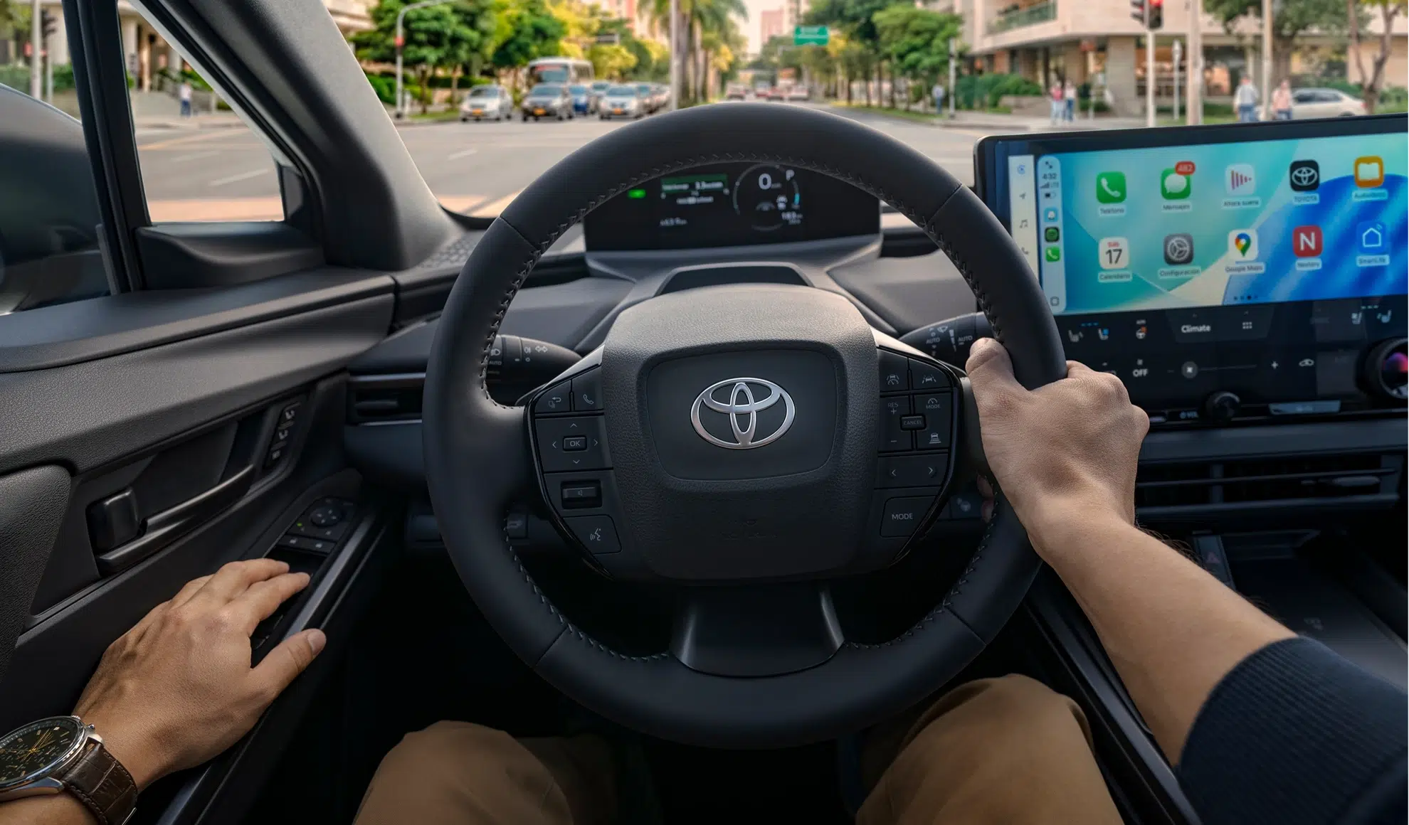 Driver's hands on a steering wheel with a digital instrument cluster ahead and a large in-dash touchscreen showing Apple CarPlay icons on the right side of the cockpit.