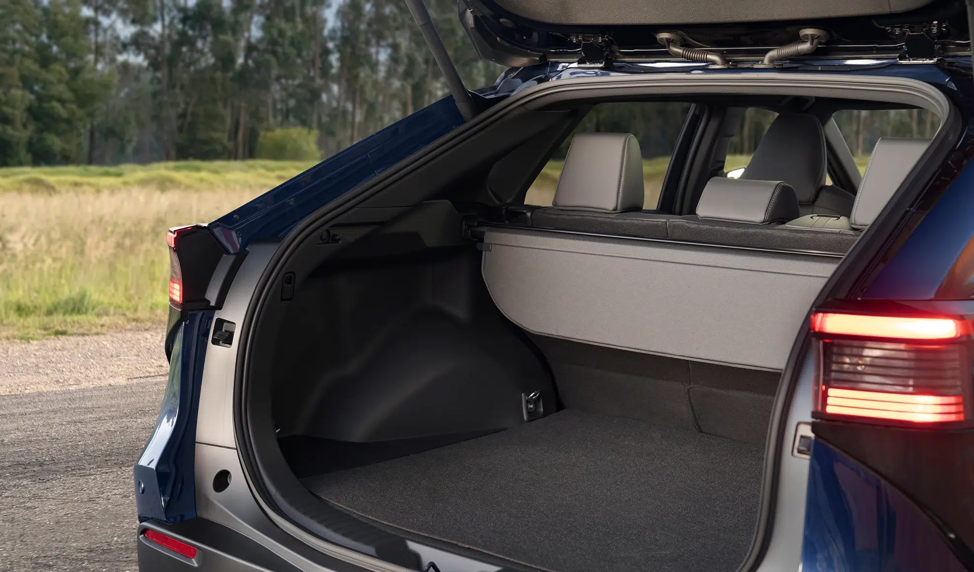 Open trunk of a blue SUV with the cargo cover in place and the rear seats visible through the opening.