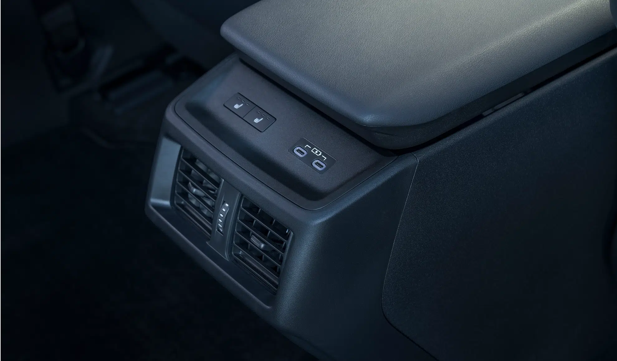 Rear center console in a car showing air vents and two USB-C charging ports for passengers in the back seat.