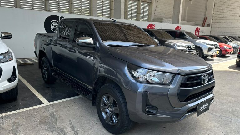 Gray Toyota pickup truck parked in a dealership lot with other cars in background.