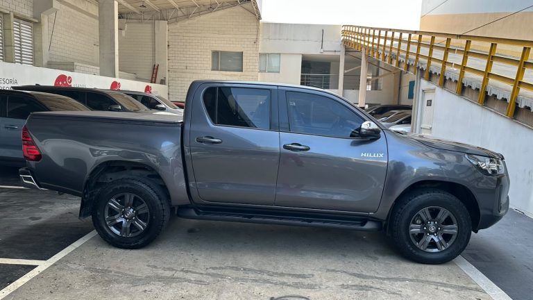 Gray Toyota Hilux crew-cab pickup parked in a lot, side view showing four doors and bed with black wheels
