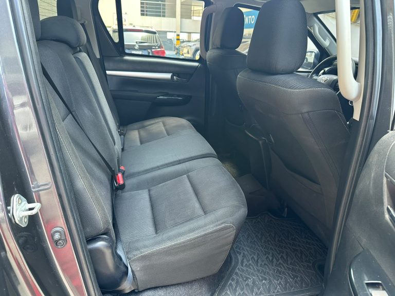 Back seat of a dark fabric SUV with a three-seat bench, headrests, and visible seat belts in use