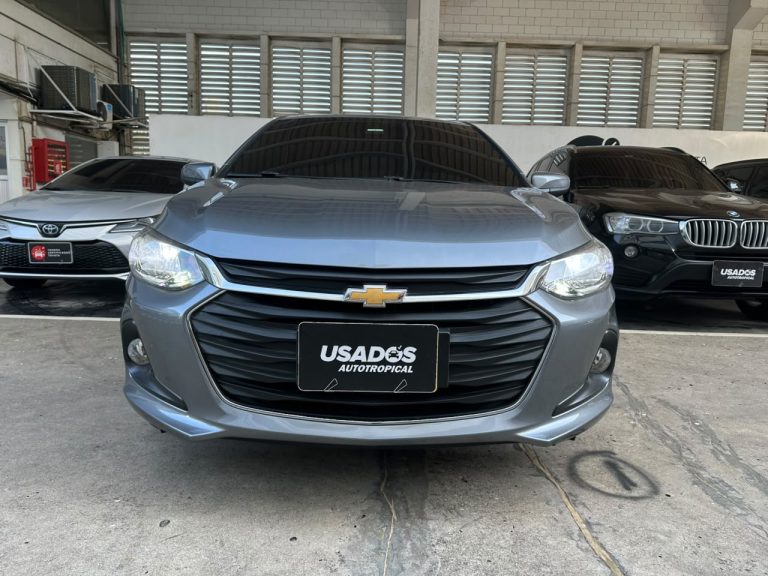 Front view of a gray Chevrolet sedan parked in a dealership lot, with a black 'USADOS AUTOTROPICAL' plate and other cars in the background.