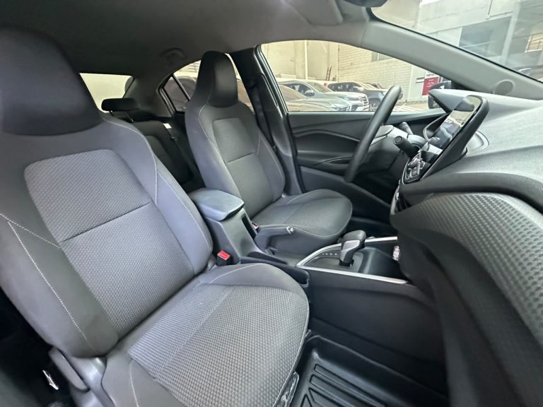 Front interior of a car showing gray cloth seats, center console, and steering wheel in view.