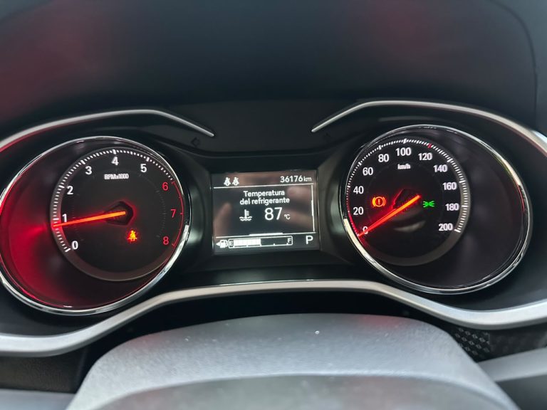 Car instrument cluster: left tachometer, right speedometer, center display shows coolant temp 87°C and odometer 36,776 km with warning icons nearby and gear in P mode