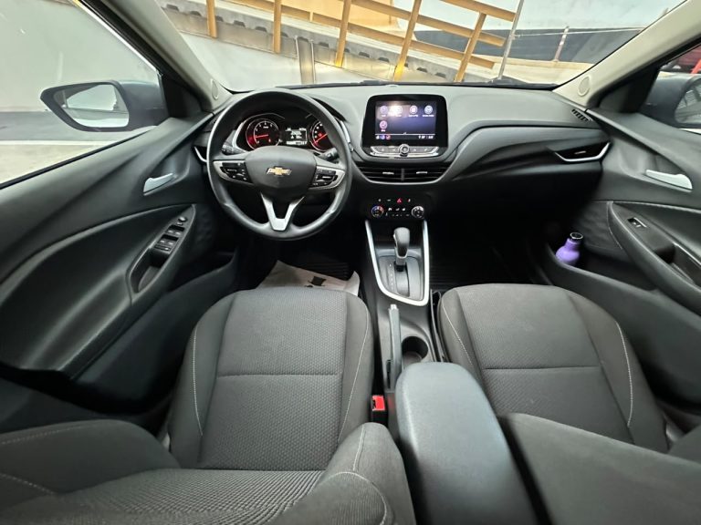 Interior view of a Chevrolet car front seat area, showing the steering wheel, center touchscreen, and gear shifter from the passenger seat perspective.