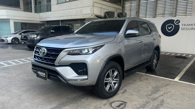 Front three-quarters view of a silver Toyota SUV parked in a dealership lot with other vehicles in the background.