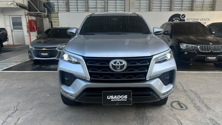 Front view of a silver Toyota SUV in a car dealership lot with other vehicles nearby, facing the camera.