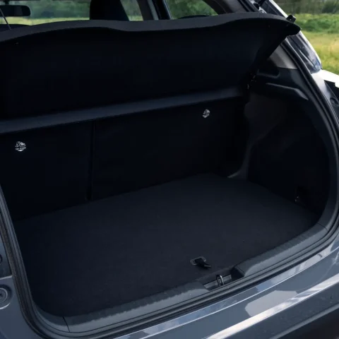 Open trunk of a dark SUV showing a flat cargo area with the rear seats folded and a retractable cover in place.
